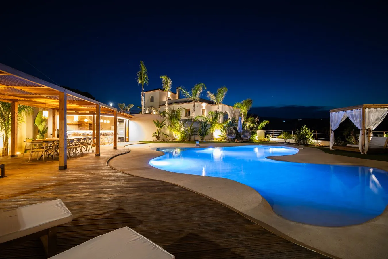 Mediterranes Haus in der Abenddämmerung mit Garten und Pool im Vordergrund