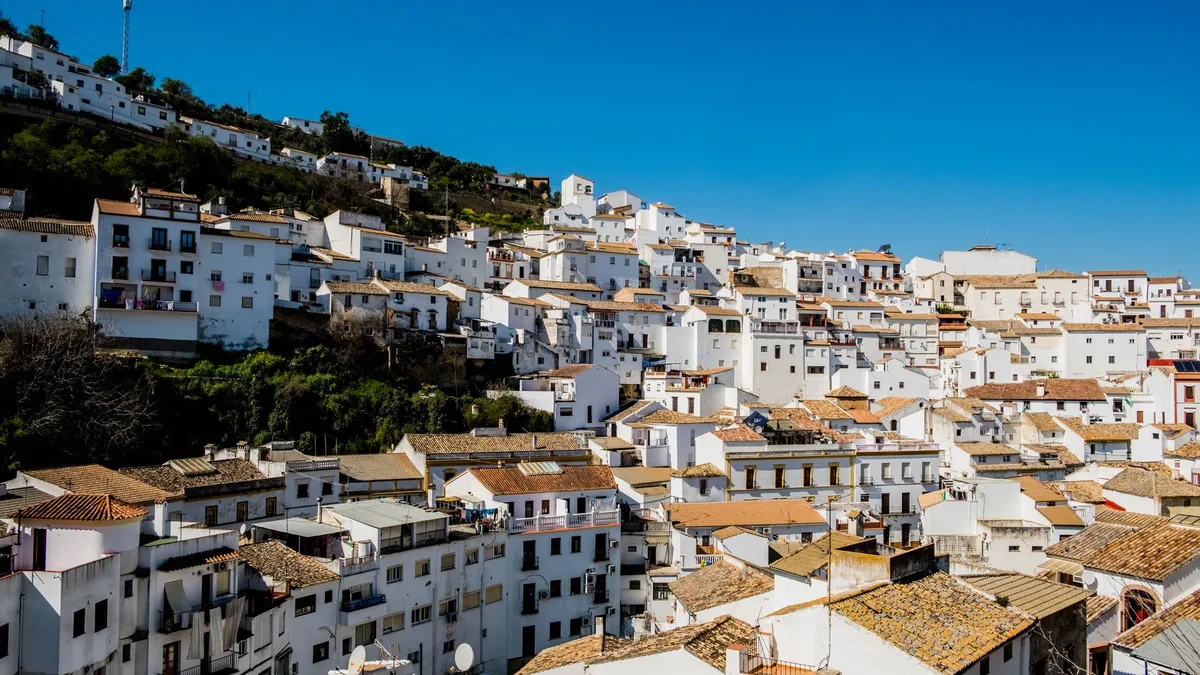 Weiß getünchte Häuser in einem Ort auf Ibiza mit sonnenbeschienenen Dächern